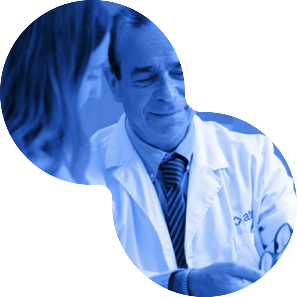 Médico con delantal de Atrys sonriendo mientras conversa con una colega