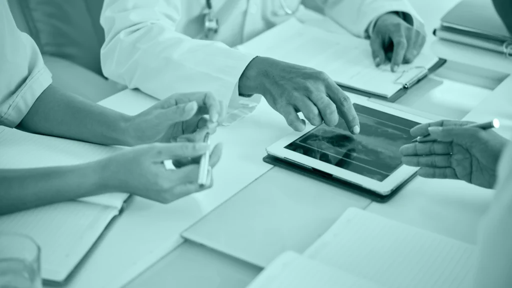 Equipo médico revisando una ecografía en una tablet durante una reunión