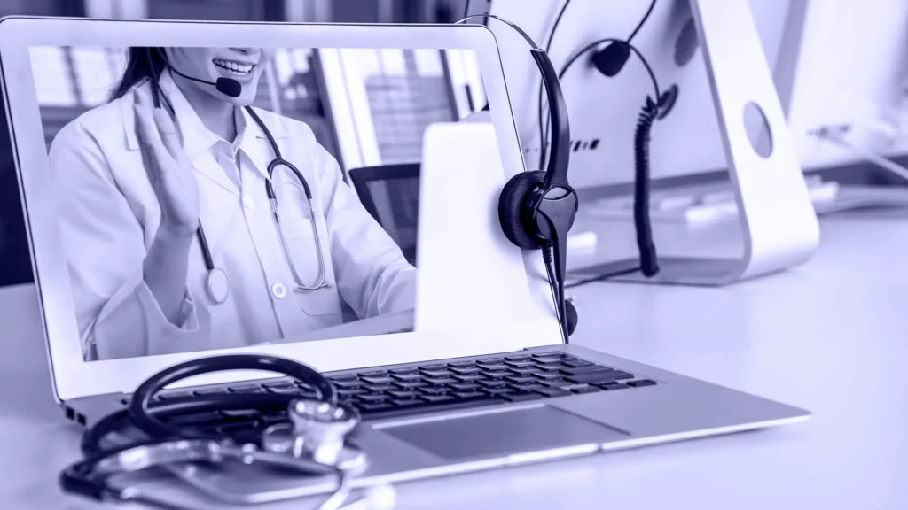 Notebook mostrando a una médica con audífonos en una teleconsulta