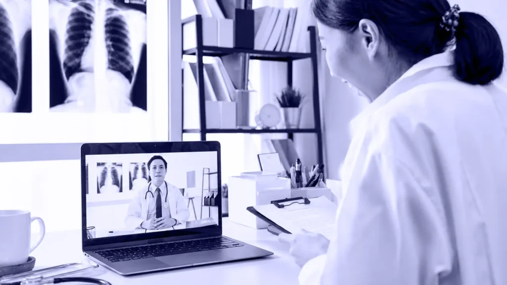 Médica en videollamada con un colega desde un notebook en su consulta
