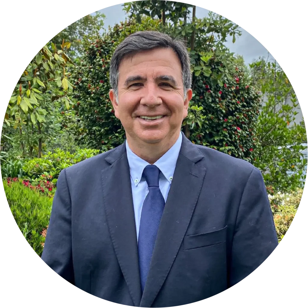 Hombre de traje azul sonriendo en un jardín, foto de testimonio