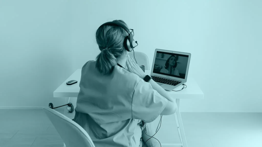 Médica con audífonos en una videollamada desde su notebook